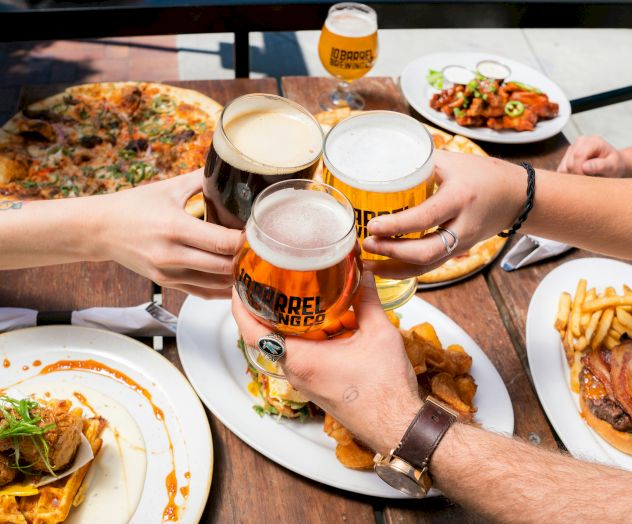 A spread of tapas and small plates with bread, olives, dips, roasted veggies, and drinks; people clinking glasses and sharing a meal.
